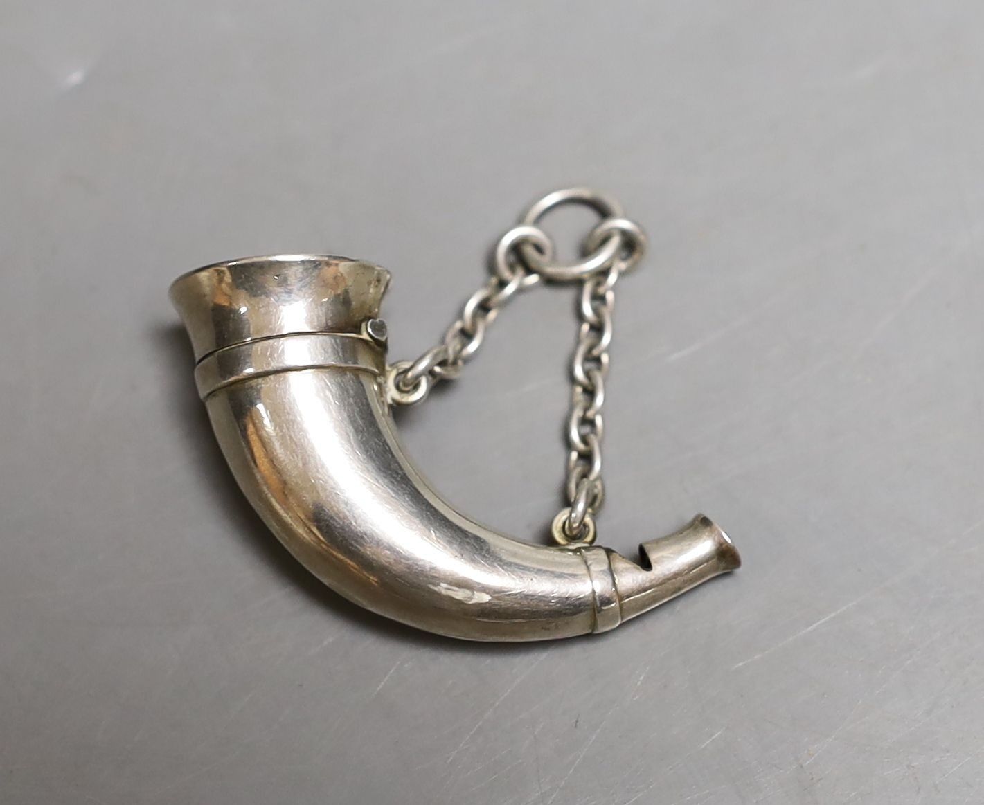 A late Victorian white metal novelty combination vinaigrette/whistle, modelled as a hunting horn, by Sampson Mordan & Co, 48mm.